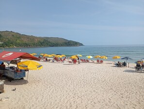Una playa con hileras de sombrillas amarillas y sillas de playa rojas.