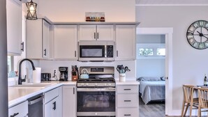 Een moderne keuken met witte kasten, een magnetron, een waterkoker en een fornuis.