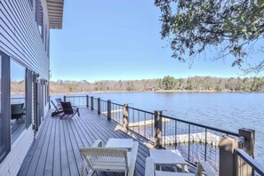 A wooden deck with outdoor seating and a view of a lake. - Eikedahls' Shoreview Cottage (Minocqua)