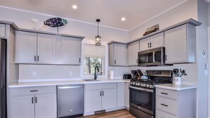 Una cucina moderna con mobili bianchi, un piano cottura in acciaio inossidabile e un forno a microonde.