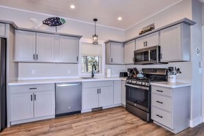 A modern kitchen with white cabinetry, a stainless steel stove, and a microwave.