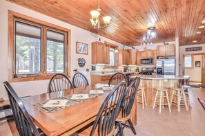 A wooden dining table with chairs, a kitchen with wooden cabinets, a microwave, and a refrigerator. - Eikedahls' Shoreview Lake House (Minocqua)