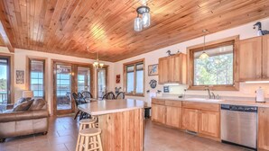 A spacious kitchen with wooden cabinets, a central island, and a dishwasher. - Eikedahls' Shoreview Lake House (Minocqua)