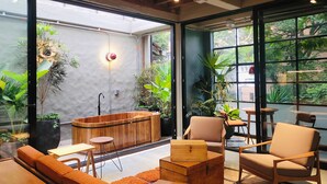 A cozy indoor space with a wooden bench, a small table, and a sofa. There are potted plants and a wooden cabinet. - 6BR Designer Retreat With Jacuzzi Near Provenza (Medellín)