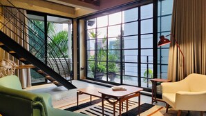A modern living room with a staircase, large windows, and a view of greenery outside. - 6BR Designer Retreat With Jacuzzi Near Provenza (Medellín)
