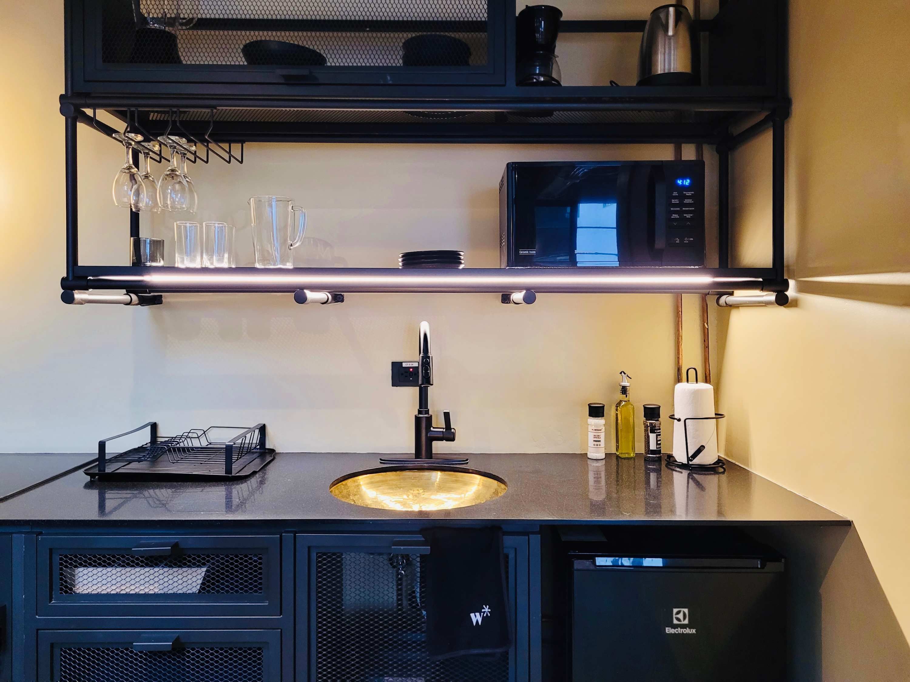 A modern kitchen with a black countertop, a sink, a microwave, and a coffee machine.