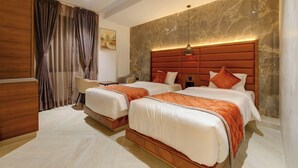 A hotel room with two beds, a wooden desk, a chair, and a large marble wall. - Hotel Diamond 26 (Surat)
