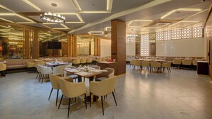 A spacious restaurant with high ceilings, modern lighting, and a variety of seating arrangements. - Hotel Diamond 26 (Surat)