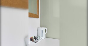 A white kettle on a white countertop with a small tray holding various items. - Charming Seaside Room | Steps from Brighton Pier (Brighton and Hove)