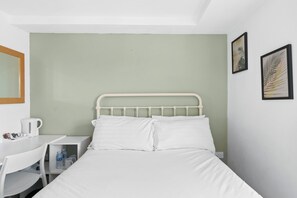 A single bed with white bedding in a room with a green wall and a white ceiling.