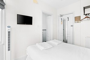 A hotel room with a bed, a television mounted on the wall, a radiator, and a door leading to a bathroom.
