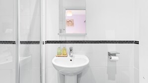 A bathroom with a white sink, a mirror, and a shower area.