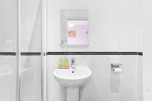 A bathroom with a white sink, a mirror, and a toilet.