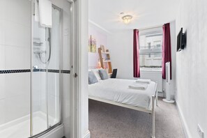 Une chambre d’hôtel avec douche, lit et vue sur l’extérieur.