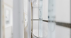 Une salle de bain moderne avec une douche à parois de verre, des murs blancs et un sol carrelé.