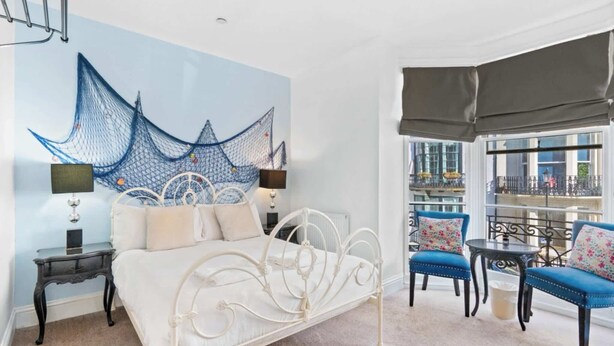 A bedroom with a bed, bedside tables, a large window with a view, and a balcony with seating. - Seaside Charm: Next to The Pier, Top Attractions (Brighton and Hove)