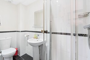 A bathroom with a toilet, sink, and shower.