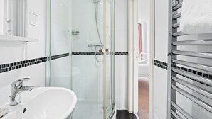 A modern bathroom with a glass-enclosed shower, a white sink, and a towel rack. - Brighton Bliss: Cozy Stay by the Pier & Marina (Brighton and Hove)