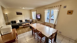 Una sala de estar con sofá, televisor, mesa y sillas.