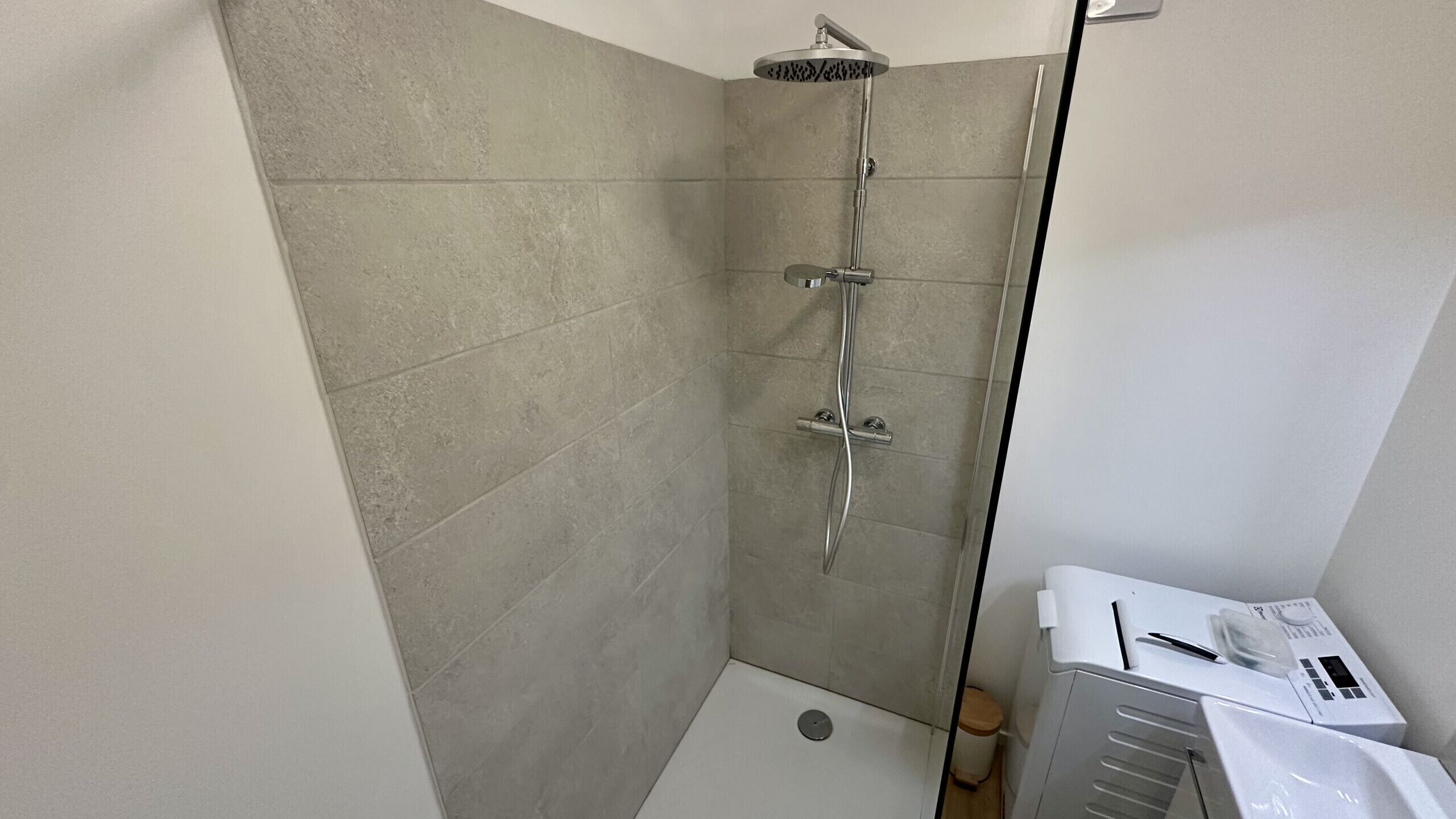 A corner shower with a handheld showerhead, a handheld showerhead, and a handheld showerhead.