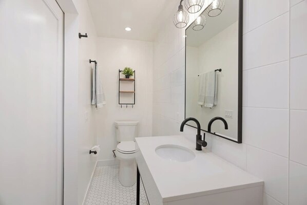 Une salle de bain moderne avec un lavabo blanc, un robinet noir et un grand miroir.