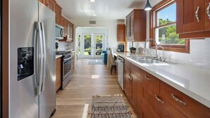 Een moderne keuken met houten kastjes, roestvrijstalen apparatuur en uitzicht op de omgeving.