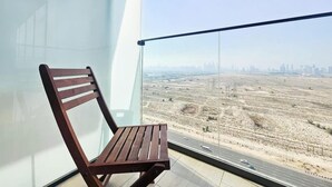 Una sedia di legno vicino a una grande finestra con vista su un paesaggio desertico e uno skyline cittadino in lontananza.