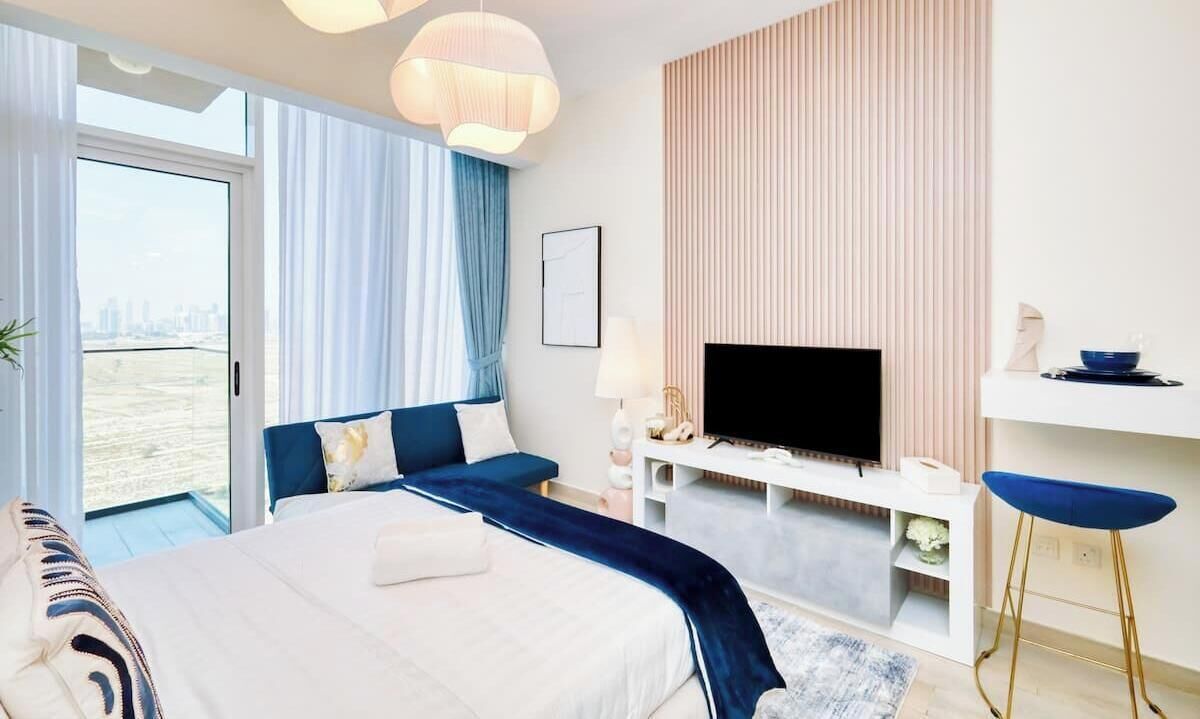 A modern hotel room with a bed, a TV, a balcony, and a view of the city.
