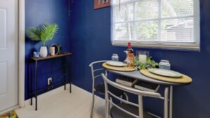 A dining area with a blue wall, a window with blinds, a small table with a plant, and a chair. - Pet-friendly Fort Lauderdale Home: 8 Mi to Beach! (North Lauderdale)