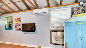 A room with a wooden ceiling, an air conditioner, a television, a window with blinds, and a colorful cabinet. - 7 Mi to Dtwn: Studio w/ Screened Porch in Tampa (Tampa)