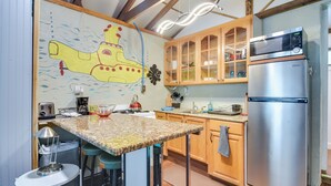 A kitchen with wooden cabinets, a stainless steel refrigerator, a microwave, and a unique submarine-themed mural on the wall. - 7 Mi to Dtwn: Studio w/ Screened Porch in Tampa (Tampa)
