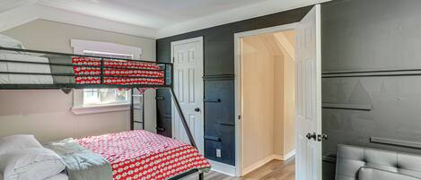 A bedroom with a bunk bed, a desk, a chair, and a wardrobe.