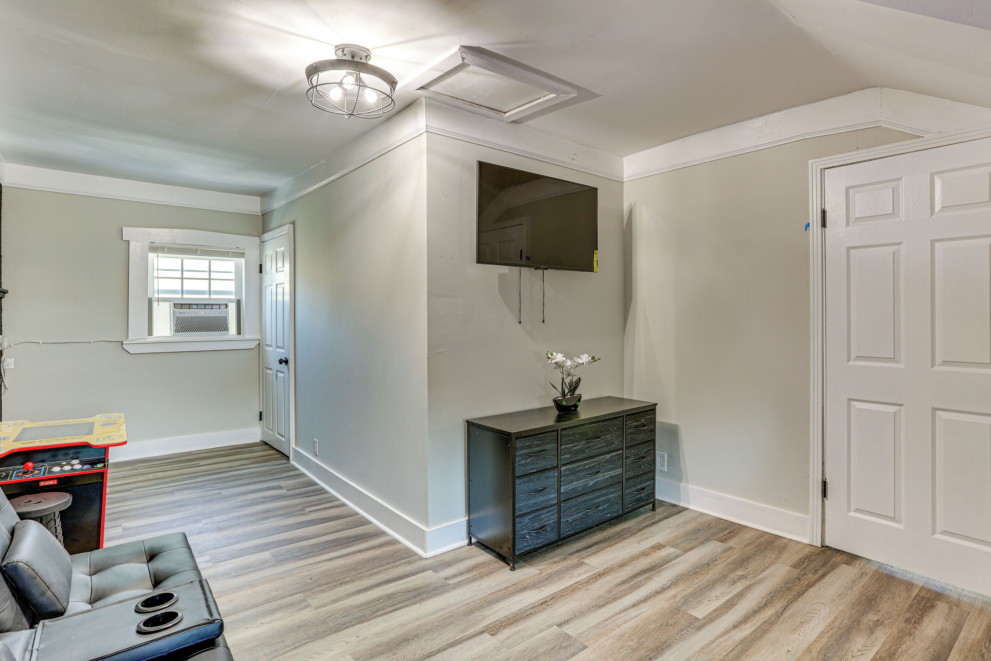 A room with a wooden floor, a black cabinet, a ceiling fan, and a door.
