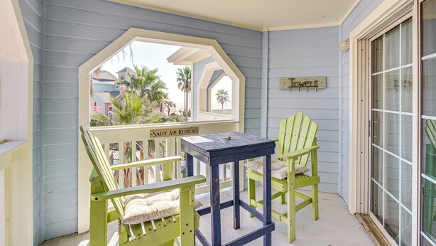Une véranda avec deux fauteuils Adirondack verts, une petite table et un panneau indiquant « Serviettes ».