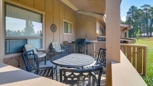 Un área de estar al aire libre techada con mesa y sillas, una parrilla y vistas del paisaje circundante.