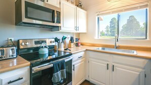 A modern kitchen with white cabinets, a stainless steel stove, a microwave, and a window with a view of trees. - Uptown Abode 4 Mi to Dtwn Pagosa Springs (Pagosa Springs)