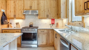Una cocina moderna con armarios de madera, electrodomésticos de acero inoxidable y encimeras de granito.