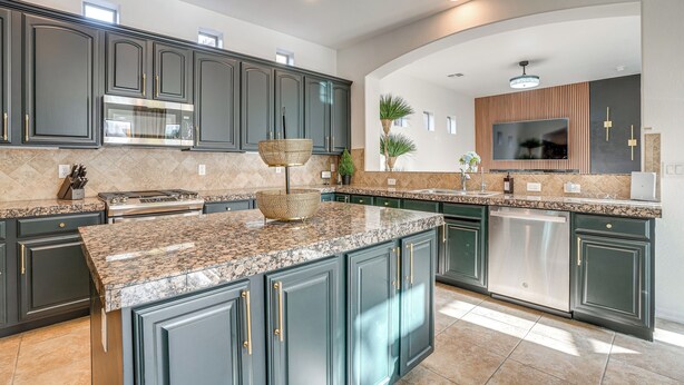A modern kitchen with dark cabinets, granite countertops, stainless steel appliances, and a built-in dishwasher. - Relax Poolside! Home 6 Mi to Camelback Ranch (Litchfield Park)
