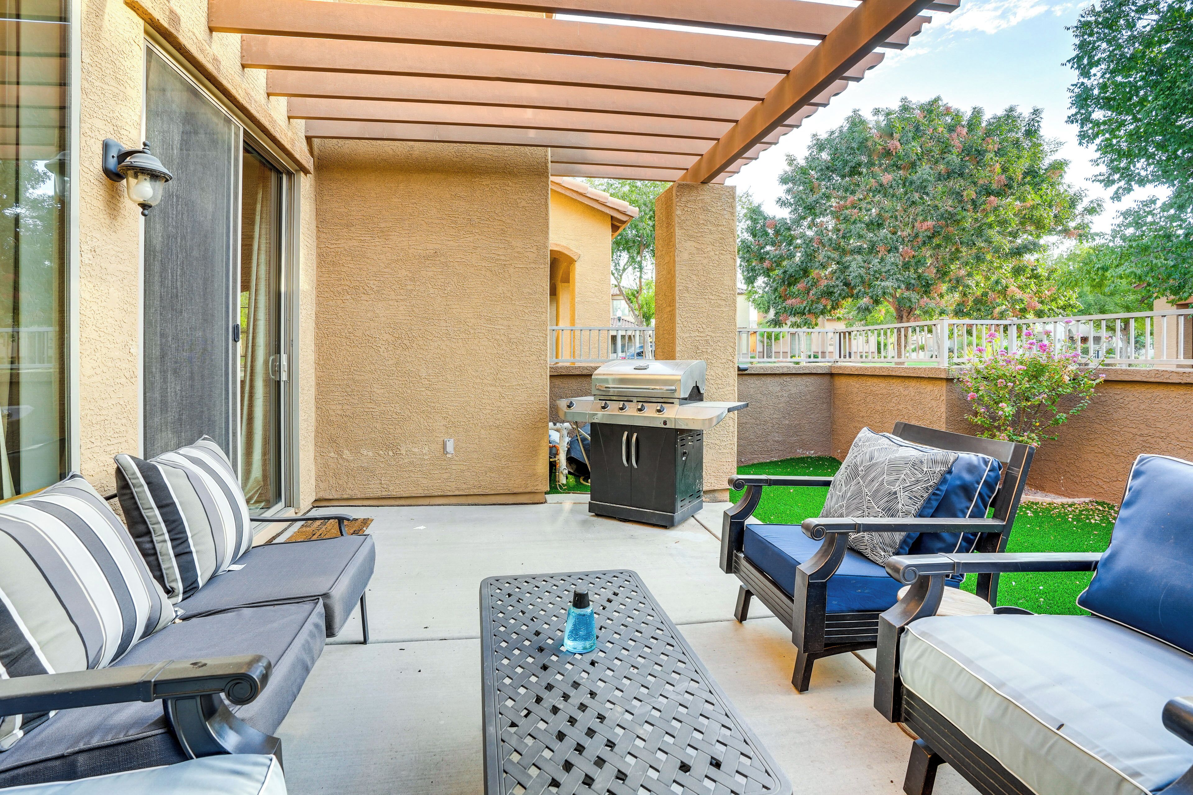 An outdoor patio with a grill, lounge chairs, and a table.