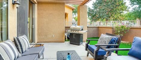 An outdoor patio with a grill, lounge chairs, and a table.