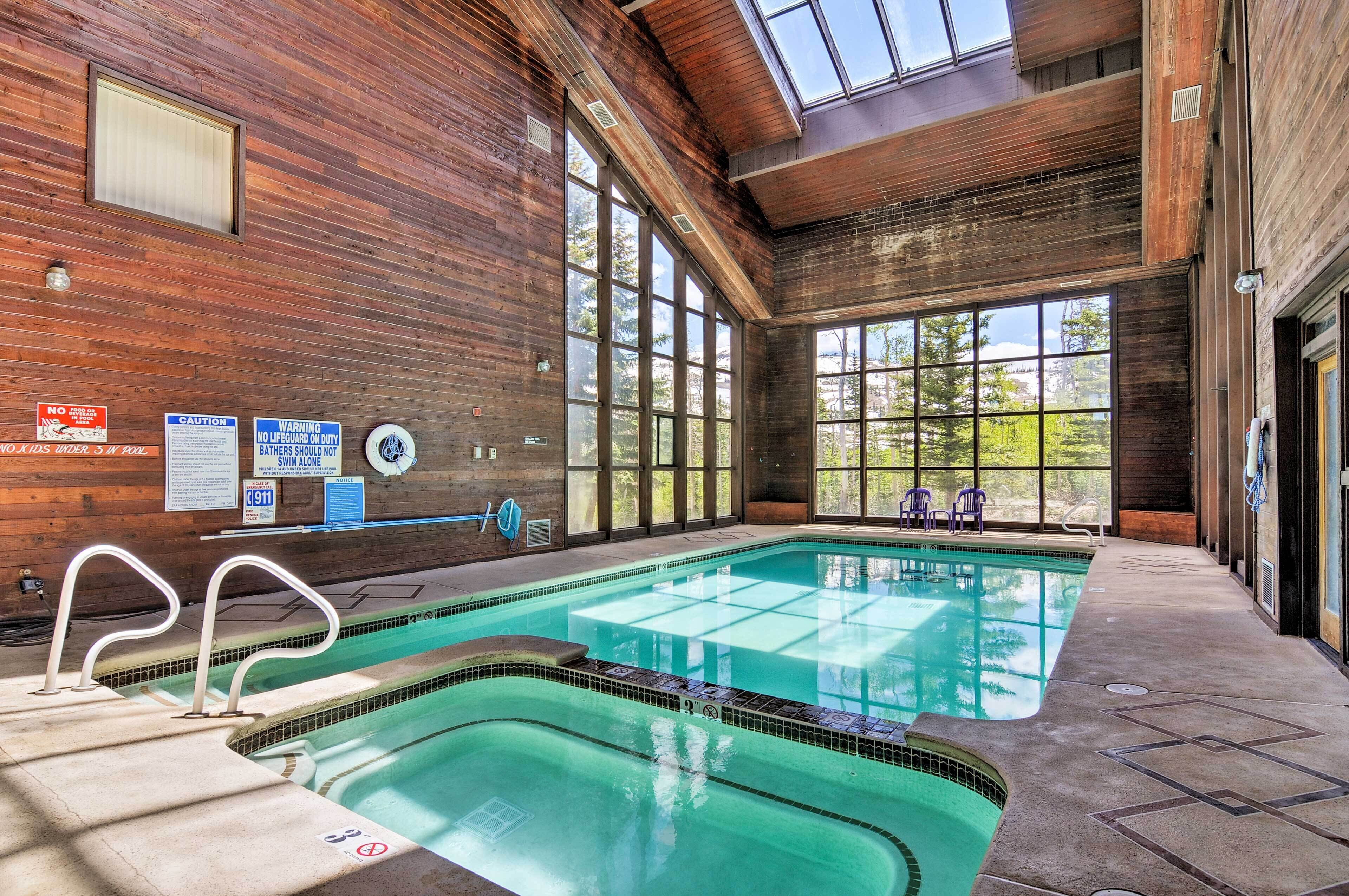 An indoor swimming pool with wooden walls, large windows, and safety signs.