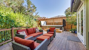 Une terrasse extérieure avec des meubles en osier, une terrasse en bois et une clôture en bois.