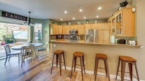 Une cuisine spacieuse dotée de meubles en bois, d’un îlot central avec des tabourets et d’un coin repas avec des chaises.