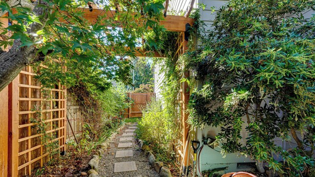 Un étroit sentier de jardin, avec des marches en bois et une clôture en bois d’un côté.