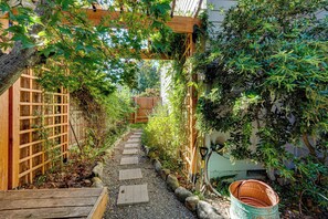 A narrow garden path with wooden steps and a wooden fence on one side. - Spacious Home w/ Swim Spa & Deck in Medford! (Medford)