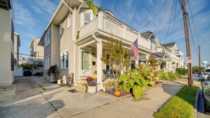 A two-story house with a front porch, a small garden, and an American flag.