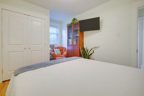 A bedroom with a bed, a wooden cabinet, a television, and a window with blinds.