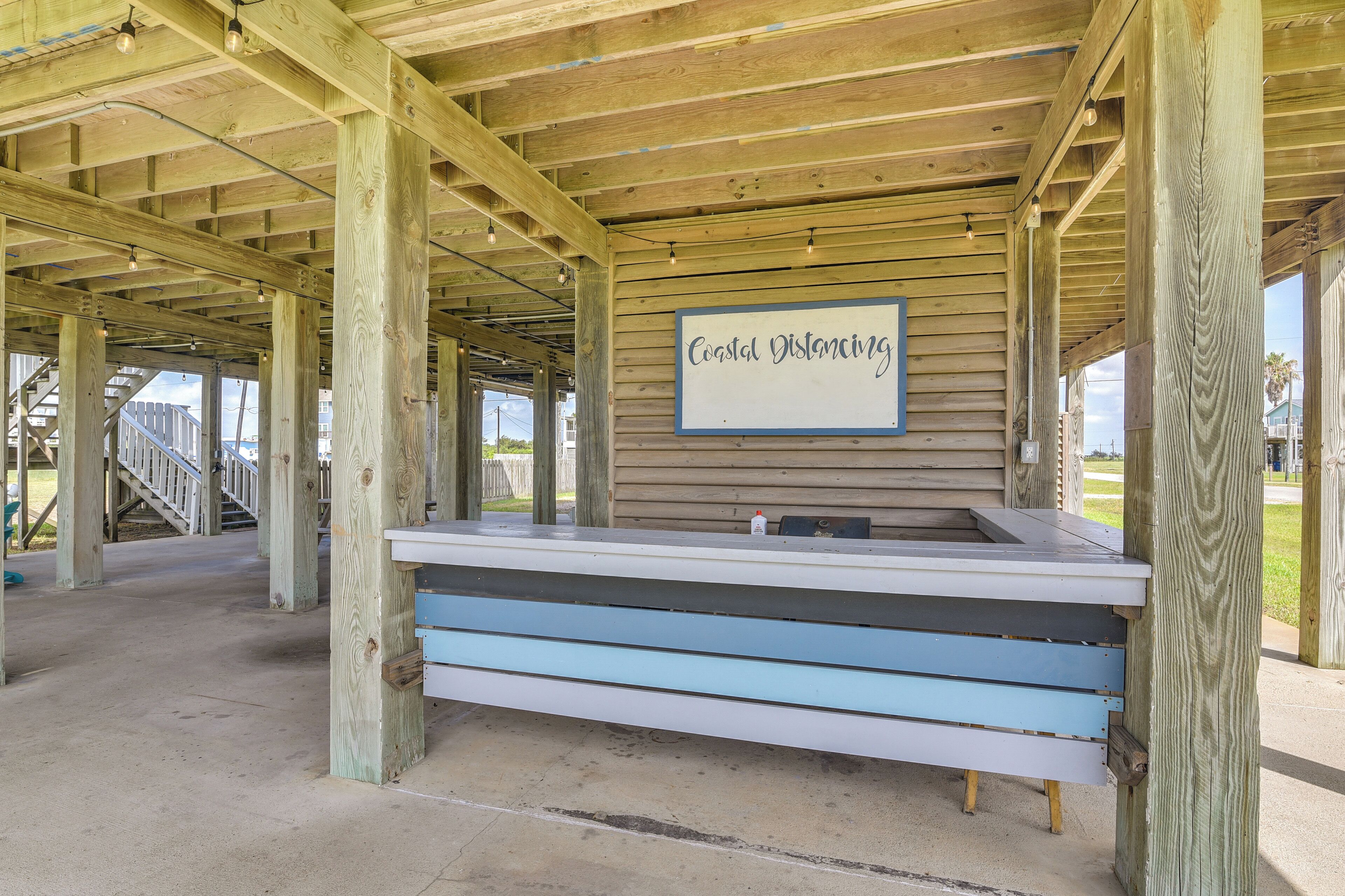 Une structure en bois sur laquelle est apposée une pancarte indiquant « Distance de sécurité en bord de mer » et à côté de laquelle se trouve un banc.
