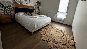 Une chambre à coucher avec un lit, un tapis tissé et un mur orné d’une fresque représentant un palmier.