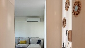 Un salon moderne avec un canapé gris, un petit tapis et des œuvres d’art décoratives accrochées au mur.